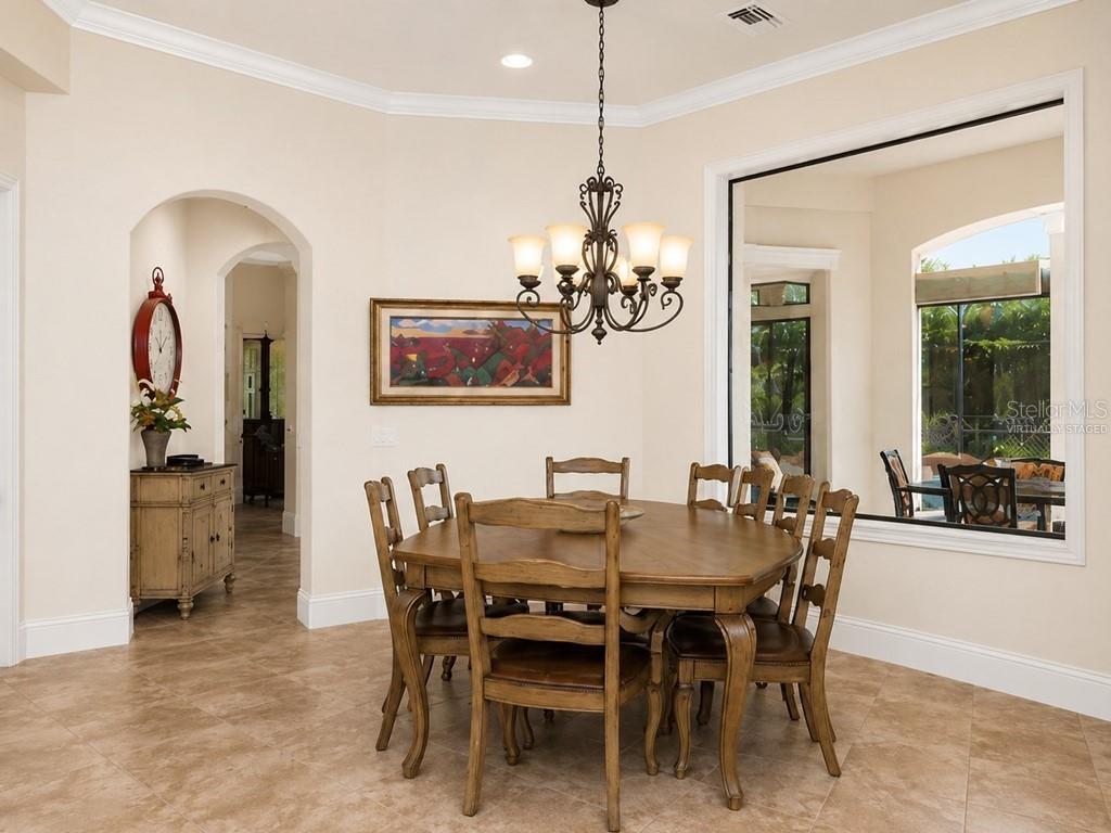 A dining room features a wooden table, chairs, a chandelier, and a large wall mirror — 8305 FARINGTON COURT, BRADENTON, FL