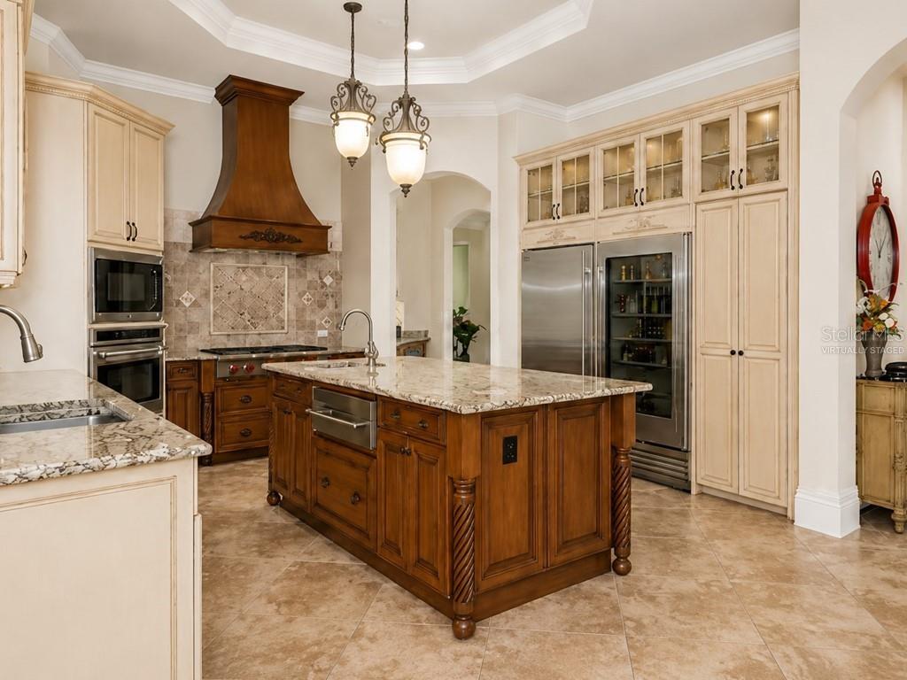 A kitchen with a large wooden island, granite countertops, stainless steel appliances, and cream cabinetry — 8305 FARINGTON COURT, BRADENTON, FL