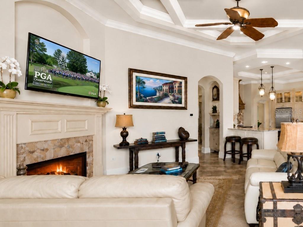 A living room features a fireplace, a wall-mounted television, and an adjacent kitchen area — 8305 FARINGTON COURT, BRADENTON, FL