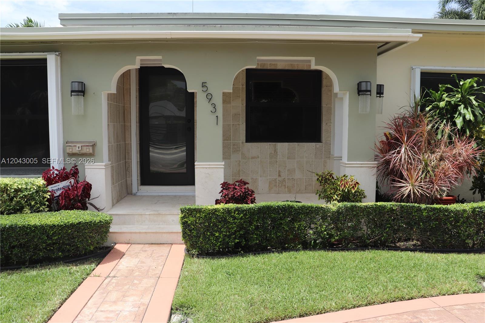 The front exterior of a house features a covered porch with arched openings and landscaping — 5931 SW 46th St, Miami FL 33155, MIAMI, FL