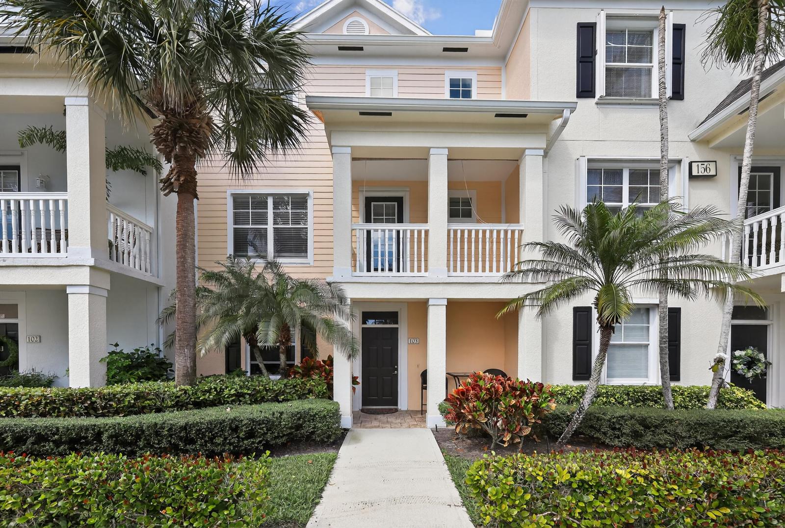A multi-story townhouse exterior features a peach-colored facade, a covered entryway, and palm trees — 156 Aragon Way, Jupiter FL 33458, JUPITER, FL