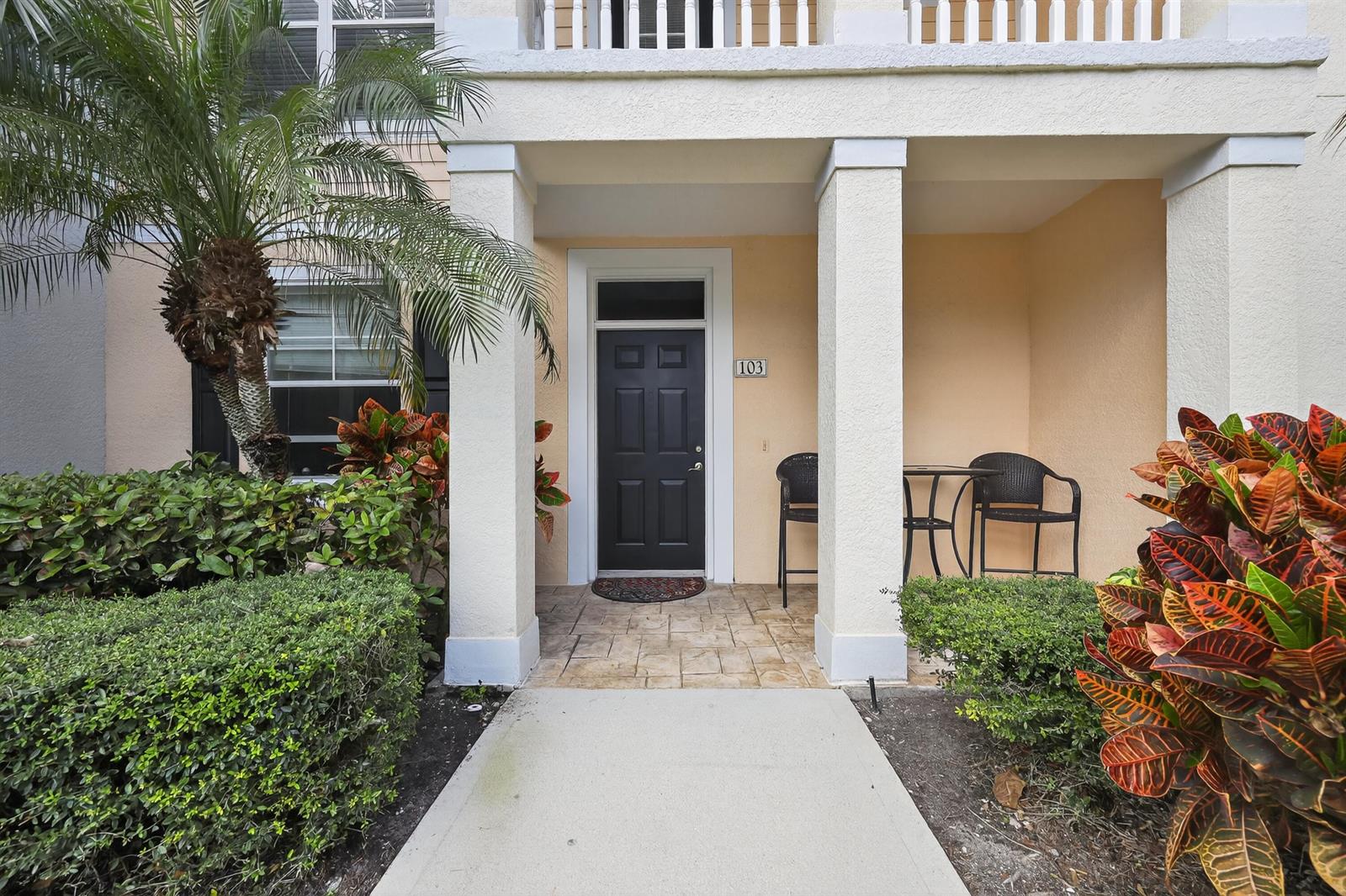 A paved walkway leads to the front entrance of a building with a black door — 156 Aragon Way, Jupiter FL 33458, JUPITER, FL