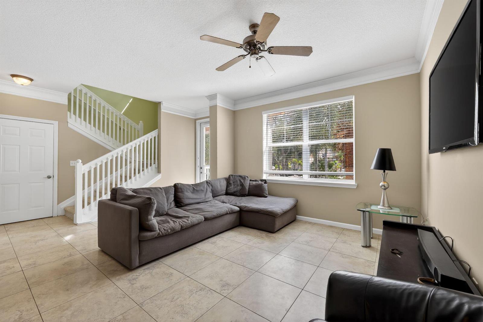 A living room features a grey sectional sofa, tiled floors, a staircase, and a ceiling fan — 156 Aragon Way, Jupiter FL 33458, JUPITER, FL