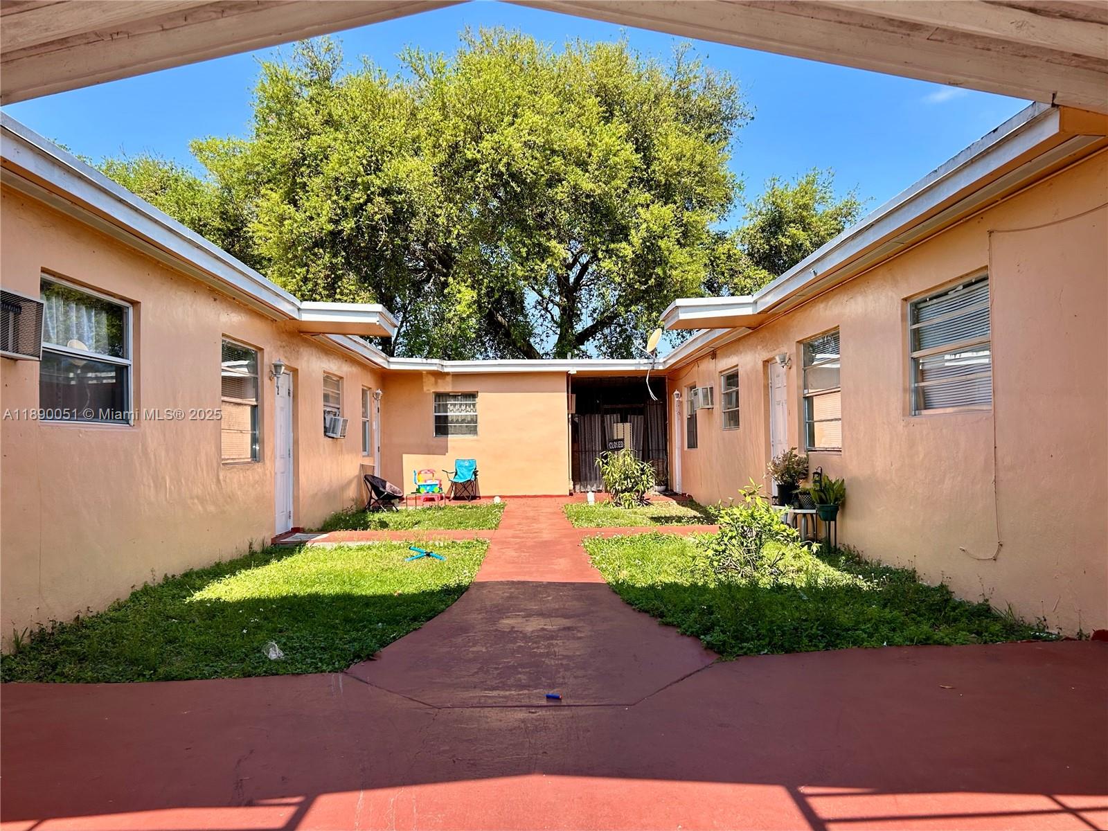 An exterior view shows a courtyard between two peach-colored buildings with a red walkway — 2013 Washington Ave, Opa-Locka FL 33054, OPA-LOCKA, FL