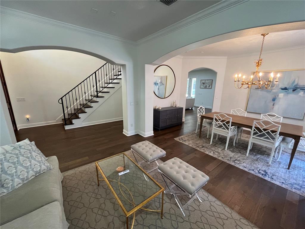 A living room and dining area feature dark hardwood floors, arched openings, and a staircase — 3820 W SAN LUIS STREET, TAMPA, FL