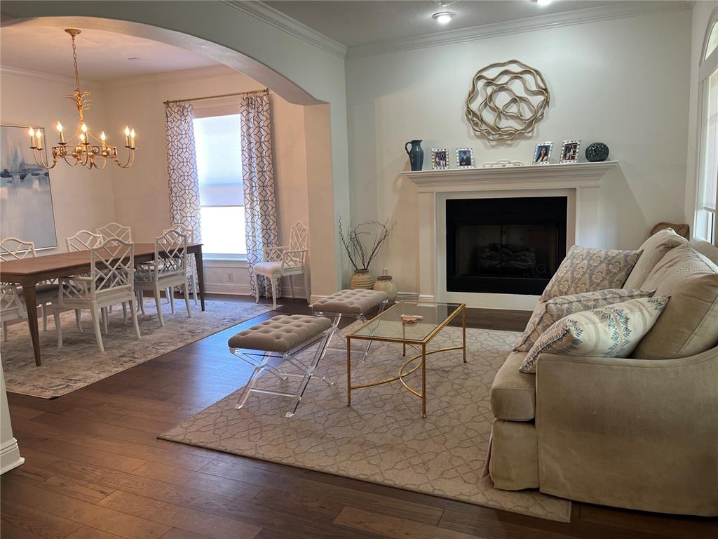 A living room with a fireplace and dining area featuring hardwood floors and neutral decor — 3820 W SAN LUIS STREET, TAMPA, FL