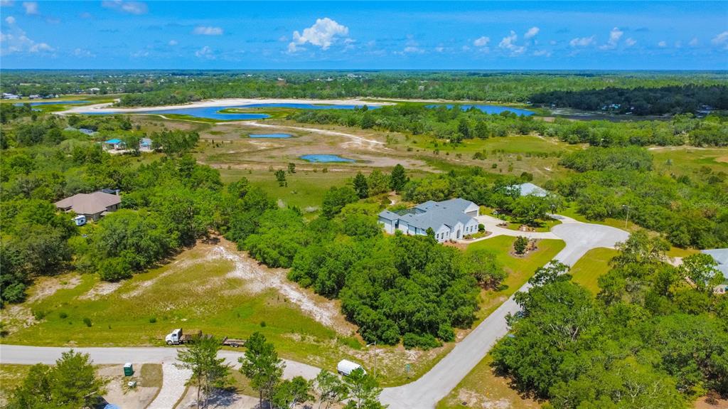 An aerial view shows a house with a gray roof surrounded by trees and wetlands — 10446 SCENIC LAKE DRIVE, WEEKI WACHEE, FL