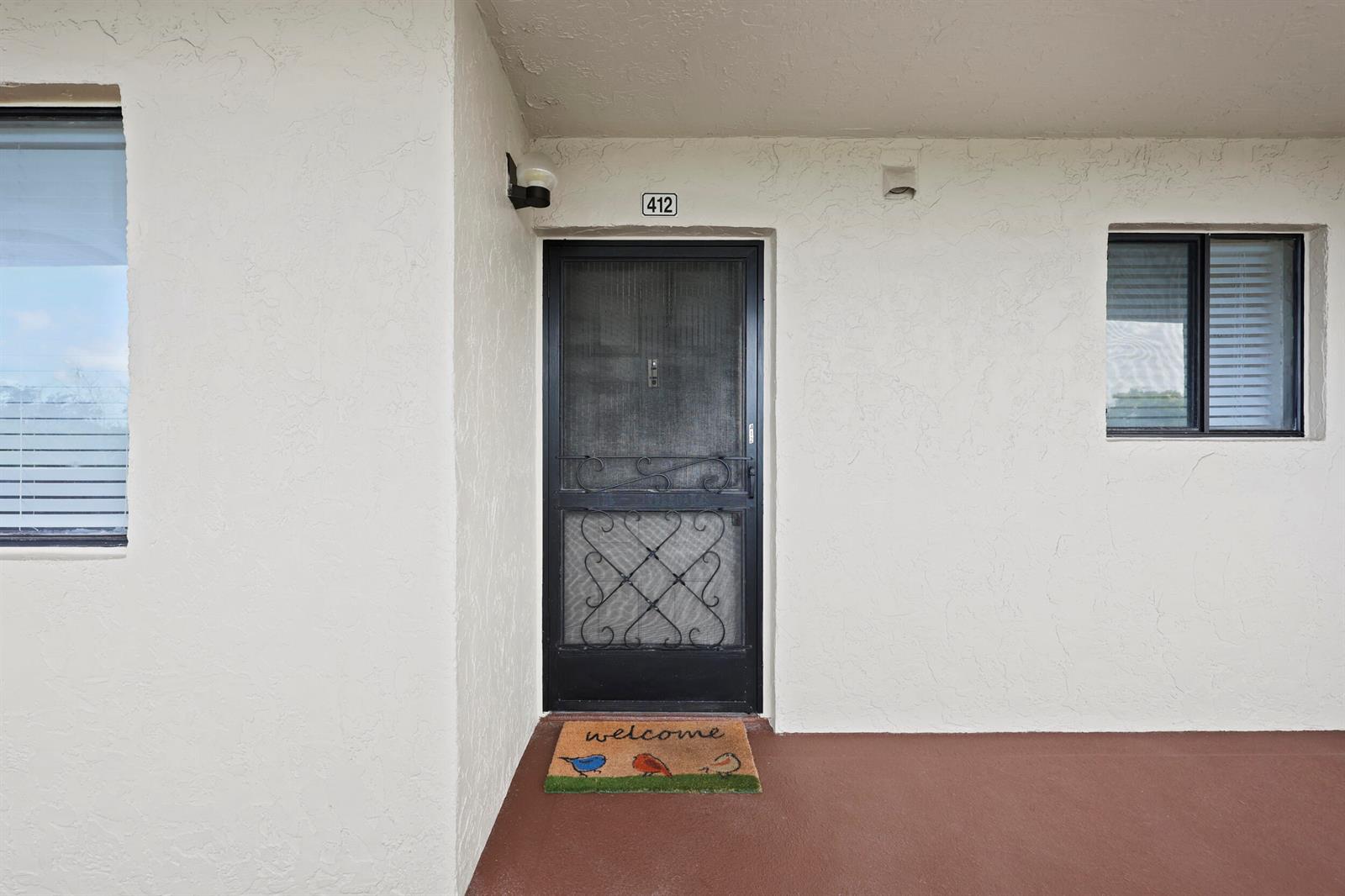 An exterior view of a building entrance with a screen door and a welcome mat — 3154 Via Poinciana # 412, FL 33467, FL