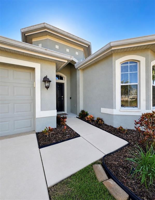 The exterior of a house features a garage, a front entrance, and a landscaped yard — 32029 GARDEN ALCOVE LOOP, WESLEY CHAPEL, FL