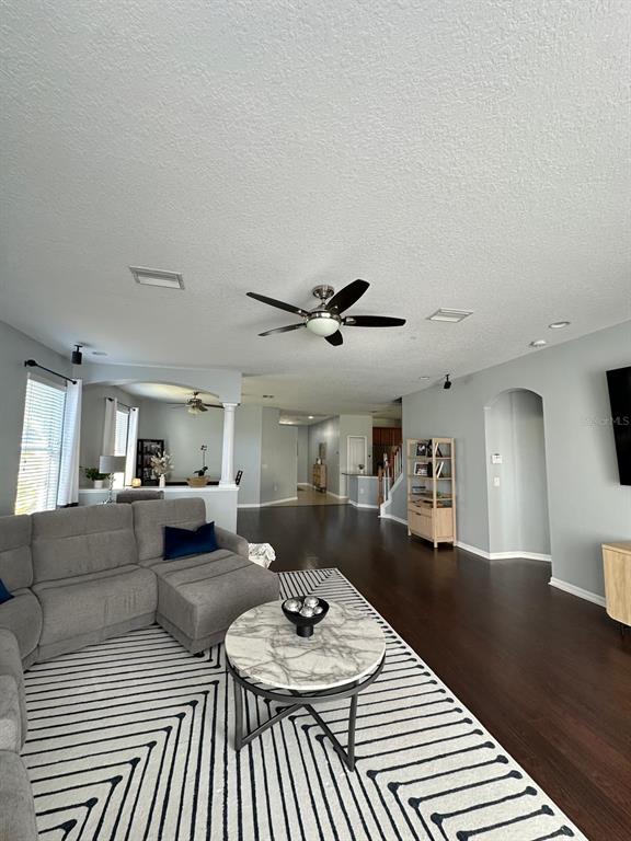 A living room features a grey sectional sofa, a marble-topped coffee table, and dark flooring — 32029 GARDEN ALCOVE LOOP, WESLEY CHAPEL, FL