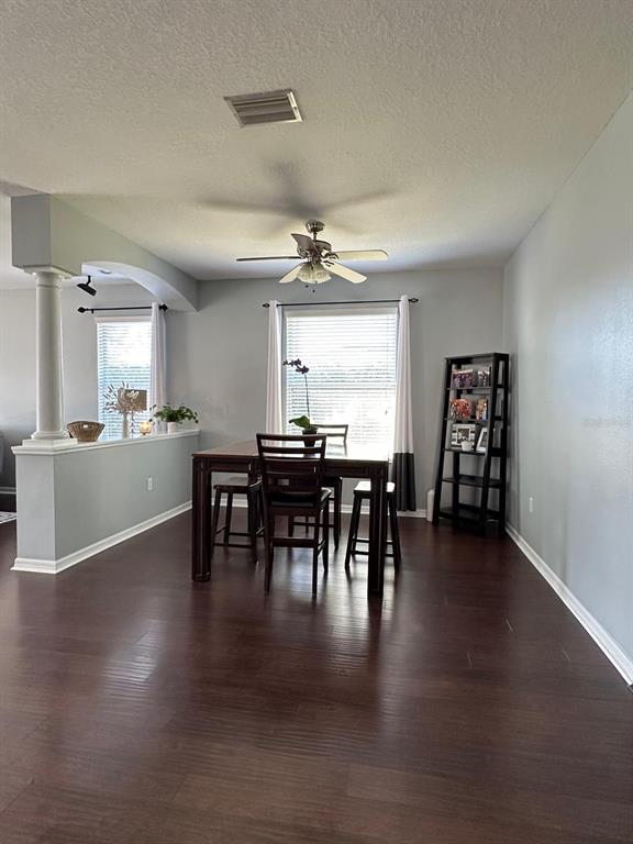 A dining area features dark wood flooring, a wooden table with chairs, and a ceiling fan — 32029 GARDEN ALCOVE LOOP, WESLEY CHAPEL, FL
