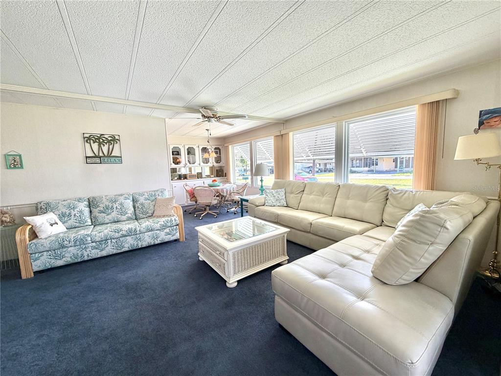 A living room features a blue patterned sofa, a white sectional, and a dining area — 408 PALO VERDE DRIVE, LEESBURG, FL