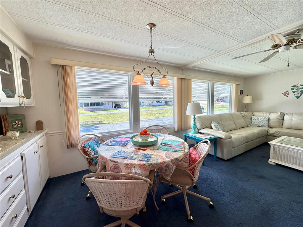 A dining area with a round table and chairs sits next to a living room — 408 PALO VERDE DRIVE, LEESBURG, FL