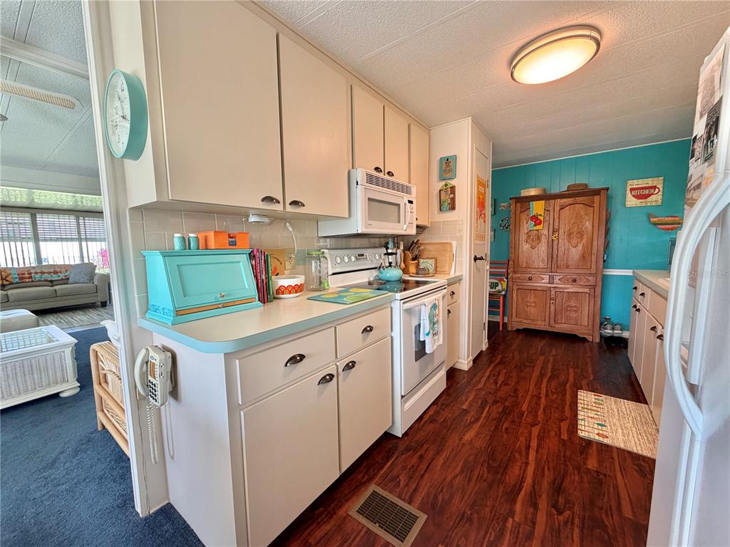 A kitchen features light-colored cabinets, a white stove, and a wooden hutch on turquoise walls — 408 PALO VERDE DRIVE, LEESBURG, FL