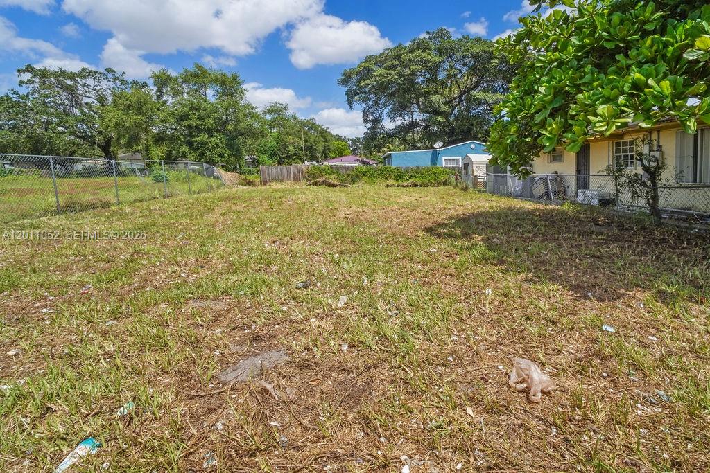 A grassy backyard with a chain-link fence and a neighboring house in the background — 2455 NW 55th street, Miami FL 33142, MIAMI, FL