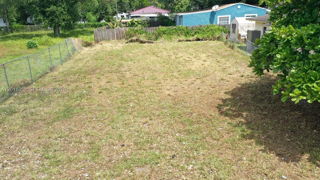 An empty, grassy residential lot is enclosed by a chain-link fence and wooden fencing — 2455 NW 55th street, Miami FL 33142, MIAMI, FL