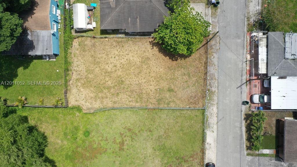 An aerial view shows a vacant, fenced residential lot situated between two houses — 2455 NW 55th street, Miami FL 33142, MIAMI, FL