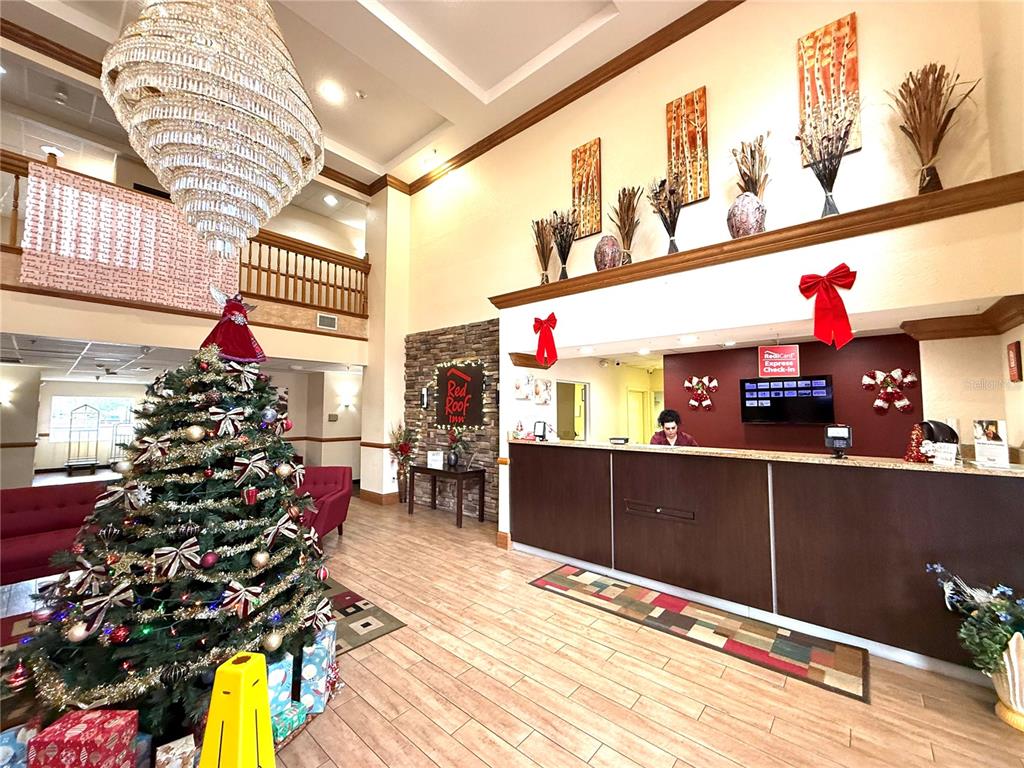 A hotel lobby features a large chandelier, a decorated Christmas tree, and a reception desk — 120 NW 40TH AVENUE, OCALA, FL