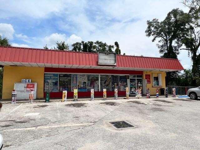 A single-story commercial building with a red metal roof and a paved parking lot — 223 E VOORHIS AVENUE, DELAND, FL