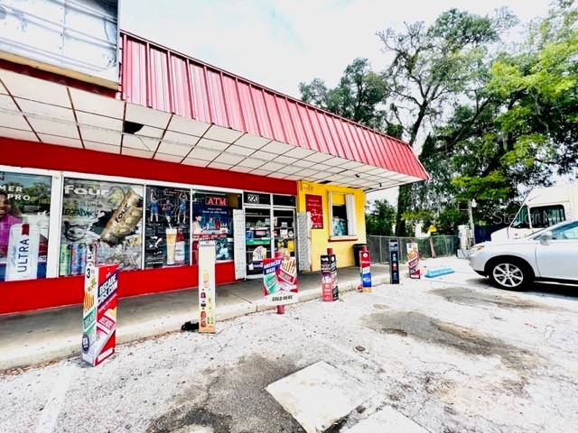 A red-roofed commercial building with large glass storefront windows and an adjacent parking lot — 223 E VOORHIS AVENUE, DELAND, FL