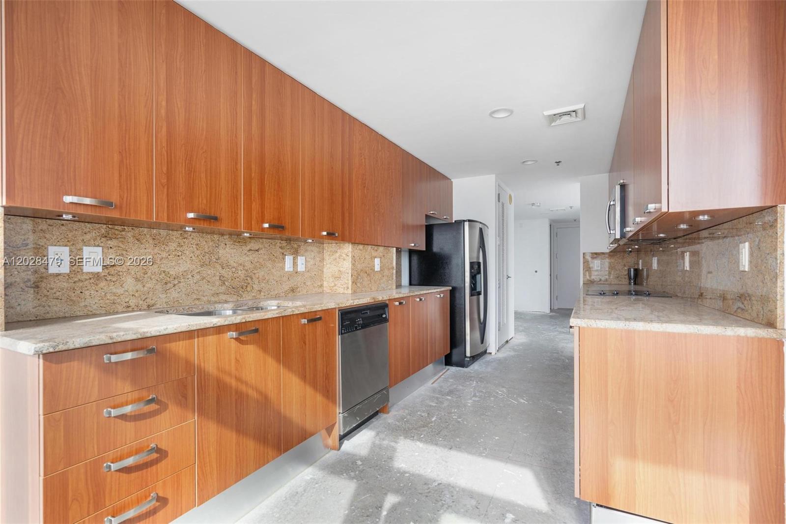 A kitchen features wood-grain cabinets, granite countertops, stainless steel appliances, and an unfinished concrete floor — 1395 Brickell Ave # 3410, Miami FL 33131, MIAMI, FL