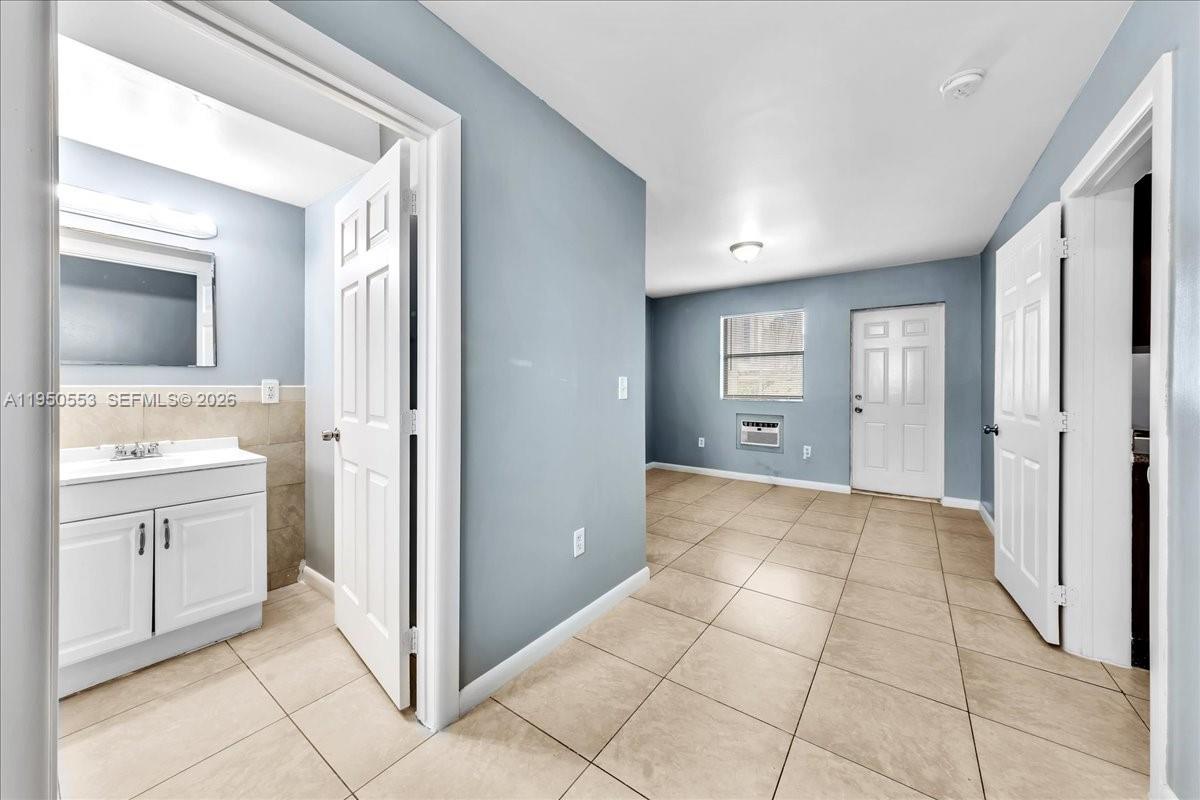 A tiled room features a bathroom entrance on the left and a white exterior door — 365 NW 8th St # 202, Miami FL 33136, MIAMI, FL