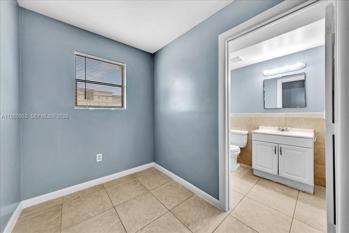 A small room with blue walls and tile flooring leads into an adjacent bathroom — 365 NW 8th St # 202, Miami FL 33136, MIAMI, FL