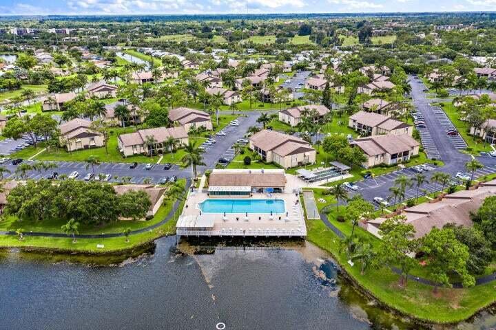 An aerial view shows a residential complex with a swimming pool overlooking a lake — 441 Pine Glen Lane # 2, FL 33463, FL