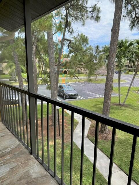 A view from a screened-in balcony overlooking a parking lot, trees, and a walkway — 441 Pine Glen Lane # 2, FL 33463, FL