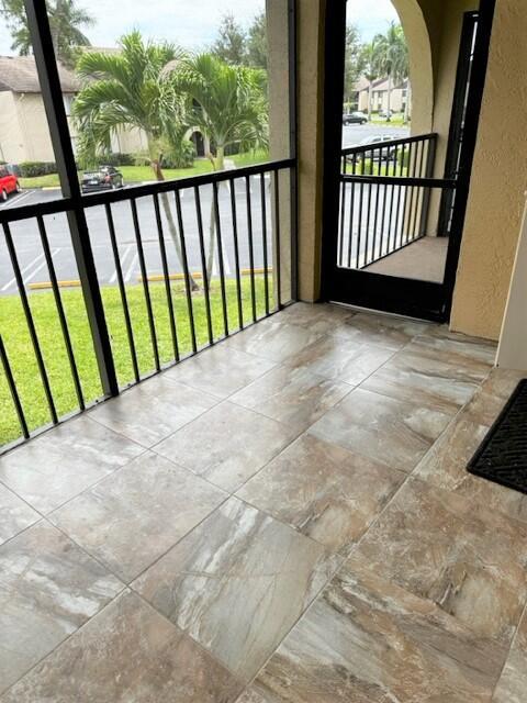 A screened-in balcony features large, earth-toned tile flooring and a view of a parking lot — 441 Pine Glen Lane # 2, FL 33463, FL