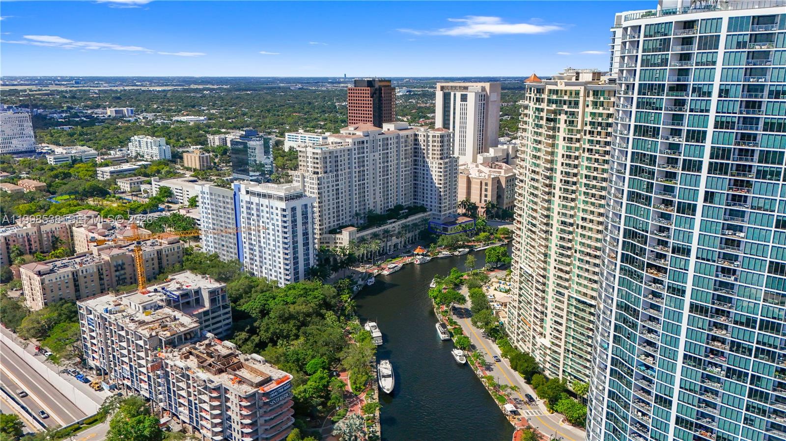 An aerial view shows a canal flowing between tall residential buildings and construction sites — FORT LAUDERDALE, FL
