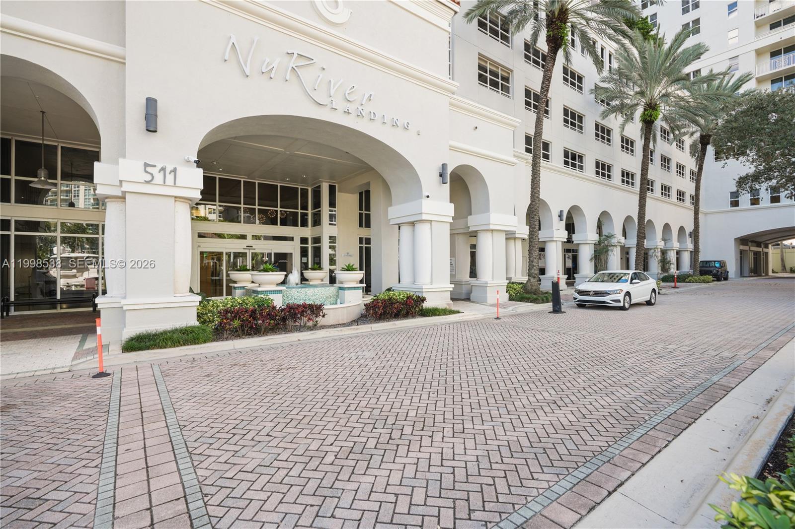 The exterior of a multi-story building features a large arched entrance with a fountain — FORT LAUDERDALE, FL