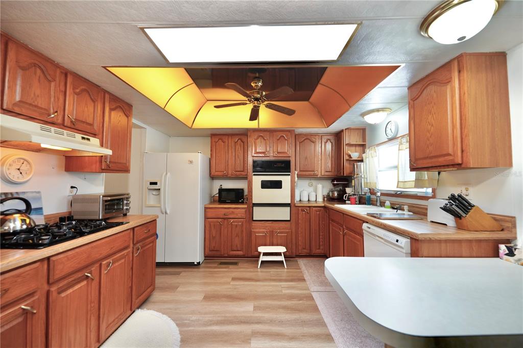 A kitchen with wood cabinets, white appliances, a ceiling fan, and a light-colored countertop — 7338 THORPP AVENUE, BROOKSVILLE, FL