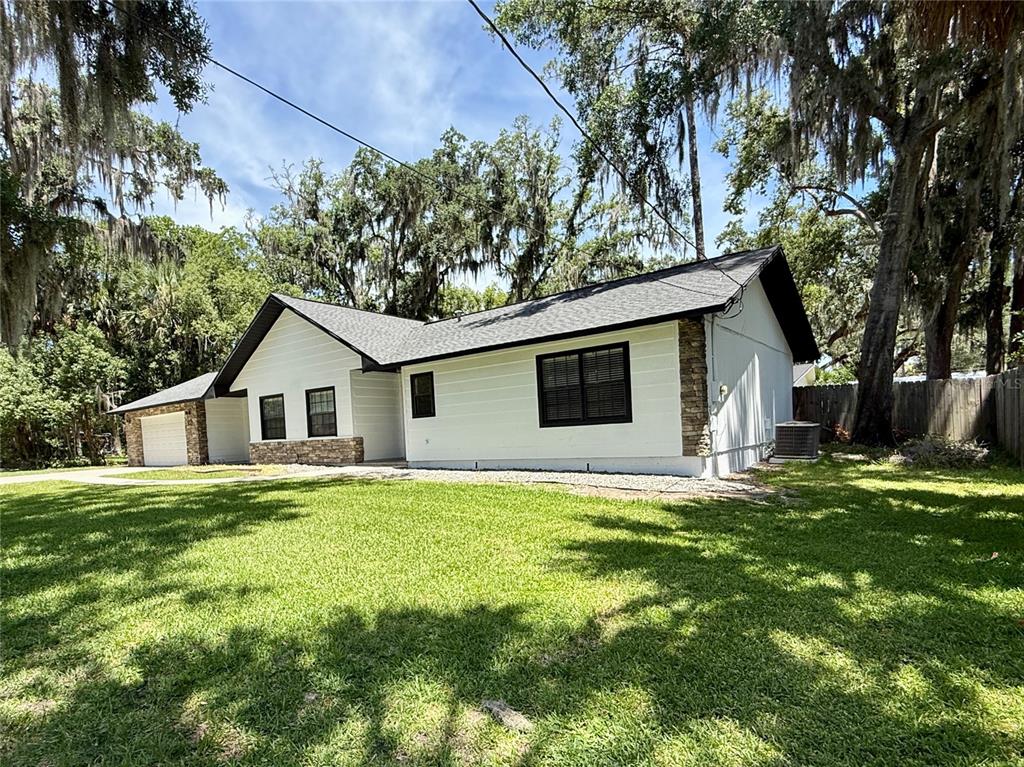 A white single-story house with a dark roof and stone accents sits on a lawn — 645 SE 21ST PLACE, OCALA, FL