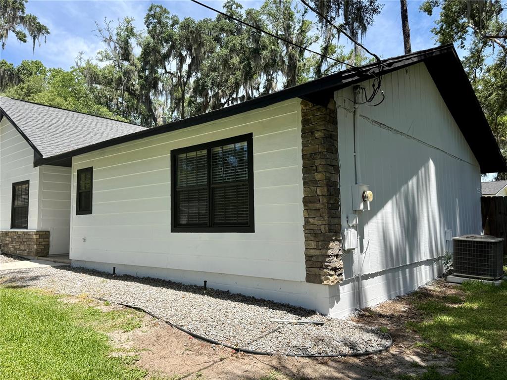 The exterior of a white house features black window frames and a stone accent column — 645 SE 21ST PLACE, OCALA, FL