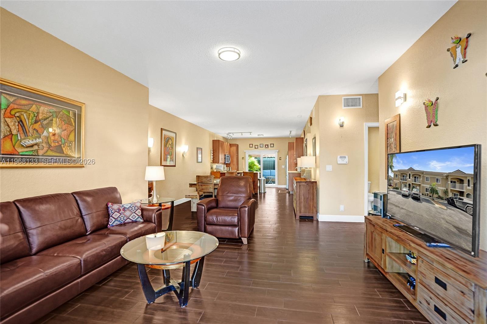 A living room with brown leather furniture, dark wood-look tile flooring, and a television console — 4812 Washington St # 3, Hollywood FL 33021, HOLLYWOOD, FL