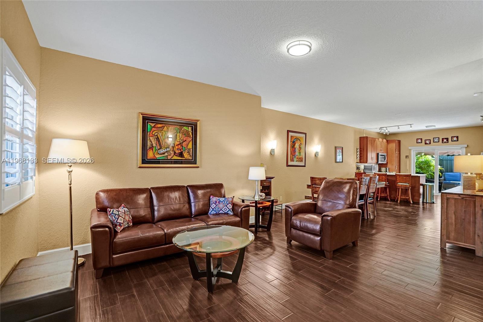 A living room with brown leather furniture, a glass coffee table, and wood-look tile flooring — 4812 Washington St # 3, Hollywood FL 33021, HOLLYWOOD, FL