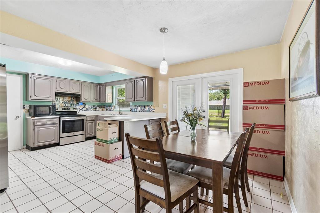 A kitchen and dining area with white tile floors, gray cabinets, and a wooden table — 5934 NW 30TH TERRACE, GAINESVILLE, FL