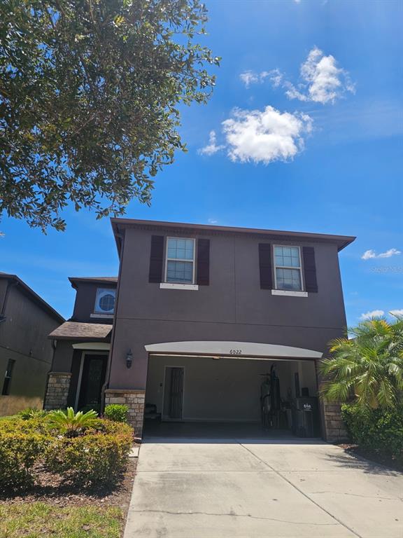A two-story house with a brown stucco exterior, stone accents, and an open garage — 6022 SWEET BIRCH DRIVE, RIVERVIEW, FL