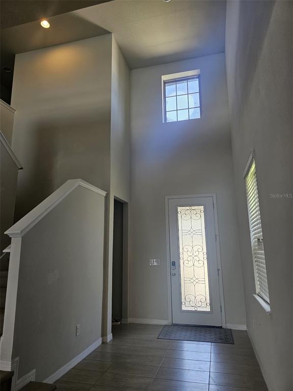 A high-ceilinged entryway features tile flooring, a staircase, and a decorative glass-paneled front door — 6022 SWEET BIRCH DRIVE, RIVERVIEW, FL
