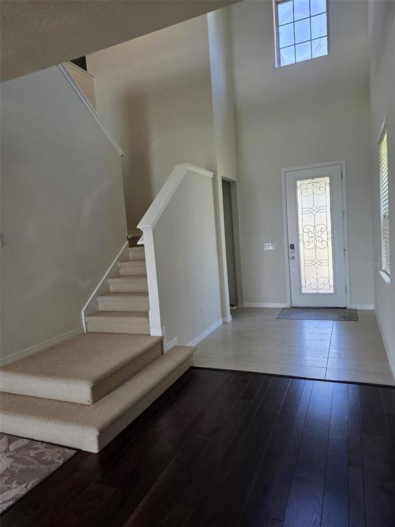 An entryway features a staircase with carpeted steps, tile flooring, and dark hardwood floors — 6022 SWEET BIRCH DRIVE, RIVERVIEW, FL