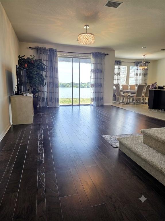 A living room with dark wood floors, a sliding glass door, and a dining area — 6022 SWEET BIRCH DRIVE, RIVERVIEW, FL