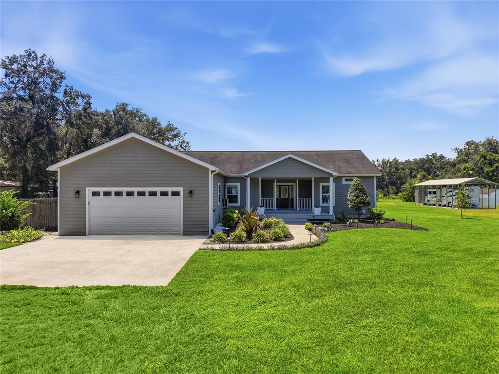 A single-story gray house with a two-car garage and a front porch sits on grass — 5335 SHAKESPEARE DRIVE, DOVER, FL