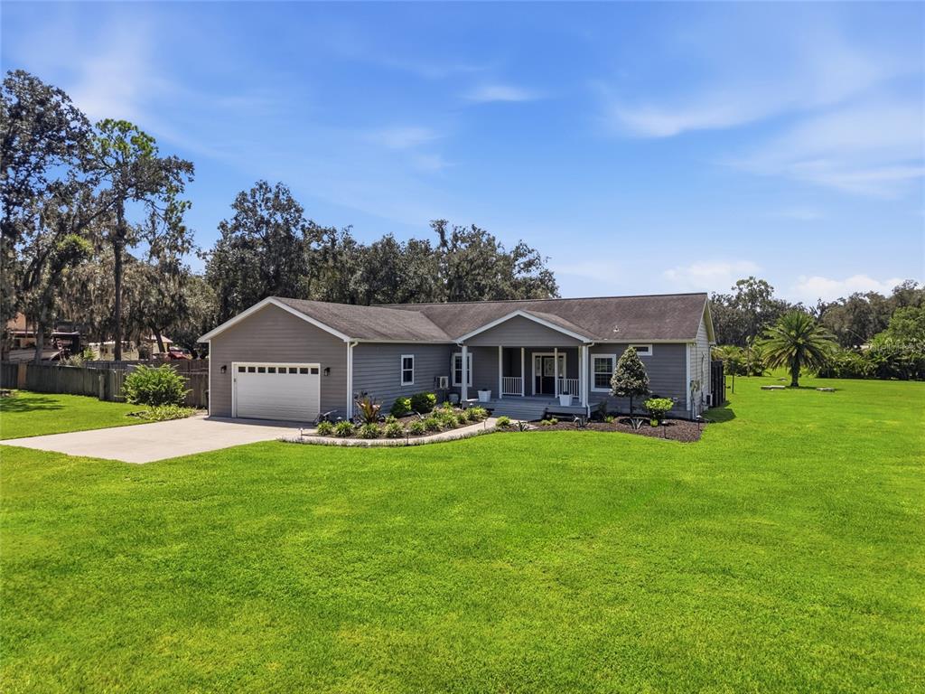 A gray single-story house with a two-car garage sits on a large, grassy lot — 5335 SHAKESPEARE DRIVE, DOVER, FL