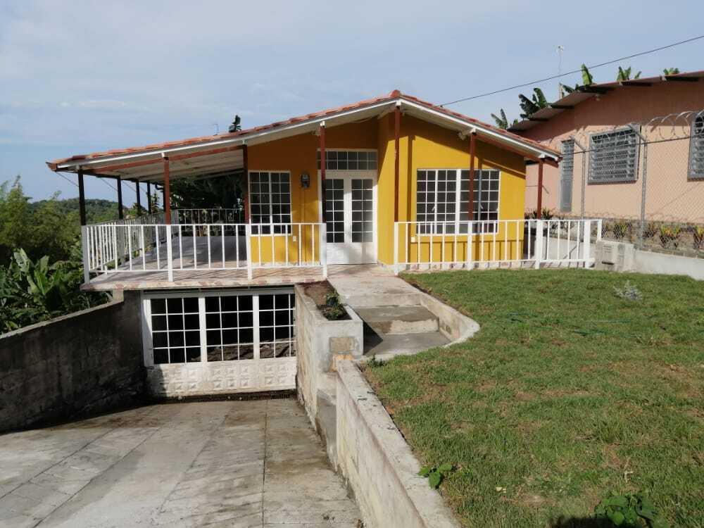 A yellow house with a covered porch, white railings, and a lower-level garage — Colombia El Hatillo, Mariquita, Tol, Co, FL