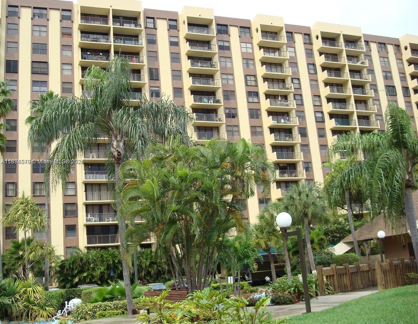 A multi-story apartment building with balconies is surrounded by palm trees and landscaping — 1470 NE 123rd St # A902, North Miami FL 33161, NORTH MIAMI, FL