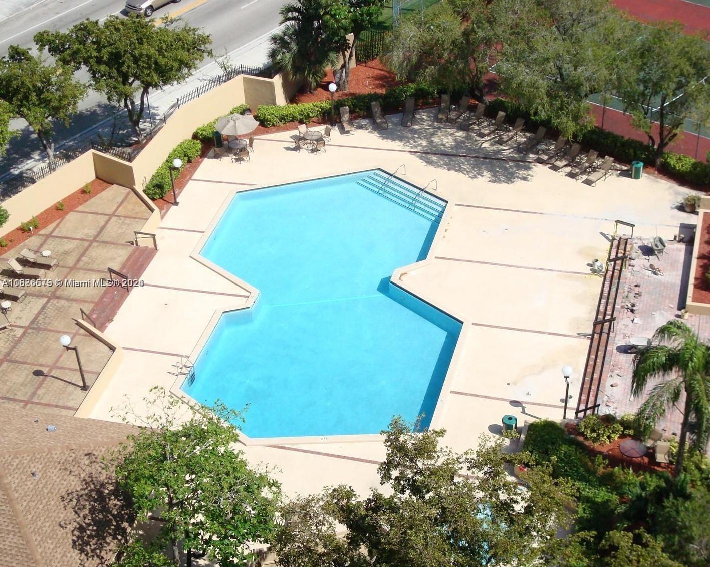 An aerial view shows a uniquely shaped swimming pool surrounded by a concrete deck and landscaping — 1470 NE 123rd St # A902, North Miami FL 33161, NORTH MIAMI, FL