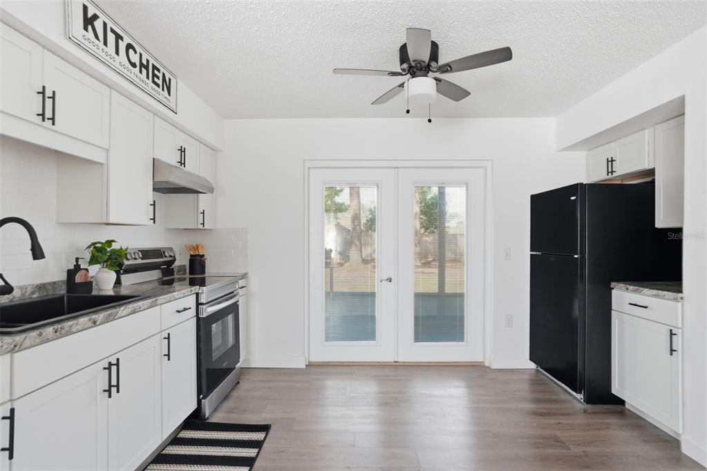 A kitchen with white cabinets, black appliances, and a ceiling fan near glass patio doors — 2076 LANDOVER BOULEVARD, SPRING HILL, FL