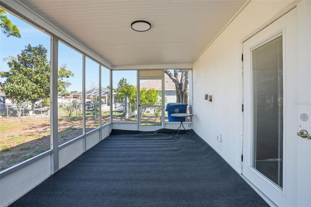 A screened-in porch with gray carpeting, a white ceiling, and a glass-paneled door — 2076 LANDOVER BOULEVARD, SPRING HILL, FL