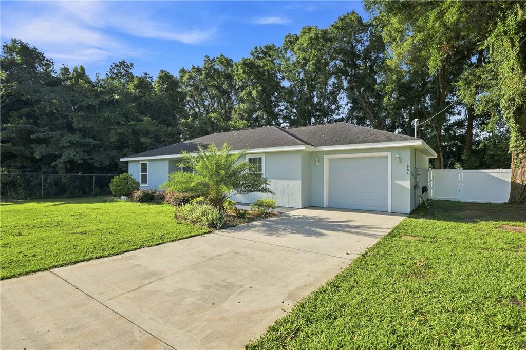 A light blue single-story house with a concrete driveway and a one-car garage — 1864 NE 126TH LANE, ANTHONY, FL